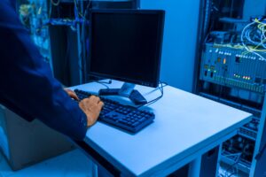 Person typing on desktop computer in server room representing in‑house IT setup for SMEs in Nairobi.