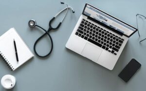 Flat lay of laptop, stethoscope, smartphone, and notebook symbolizing managed IT support for hospitals and clinics in Kenya.