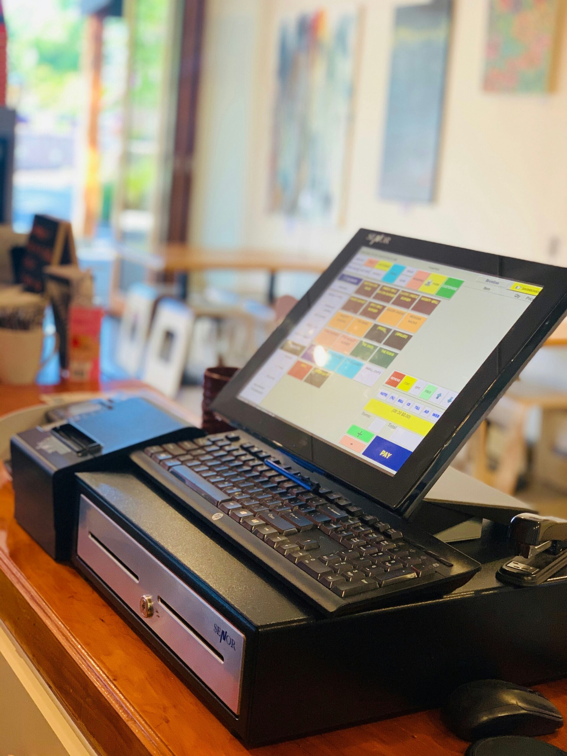 Touchscreen POS system with cash drawer and receipt printer in café environment representing modern retail transactions in Kenya.